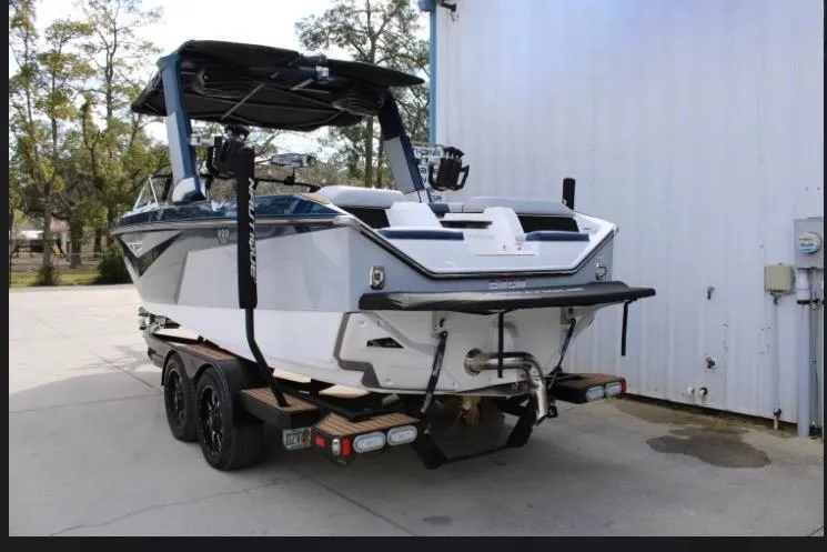 Slide: The Image of 2022 Nautique Super Air Nautique S23 boat on trailer, parked near a building. - 20