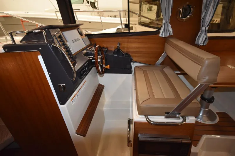 Slide: The Image of 2022 Ranger Tugs R-27 helm with Garmin navigation, wood accents, and cushioned seating. - 11