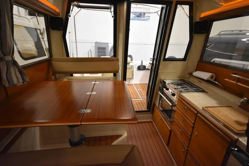 Slide: The Image of 2022 Ranger Tugs R-27 interior with wood table, kitchenette, and seating area. - 15