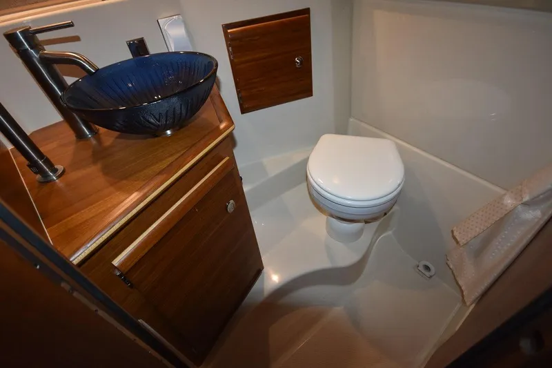 Slide: The Image of 2022 Ranger Tugs R-27 bathroom with modern sink and toilet, featuring wood accents. - 29