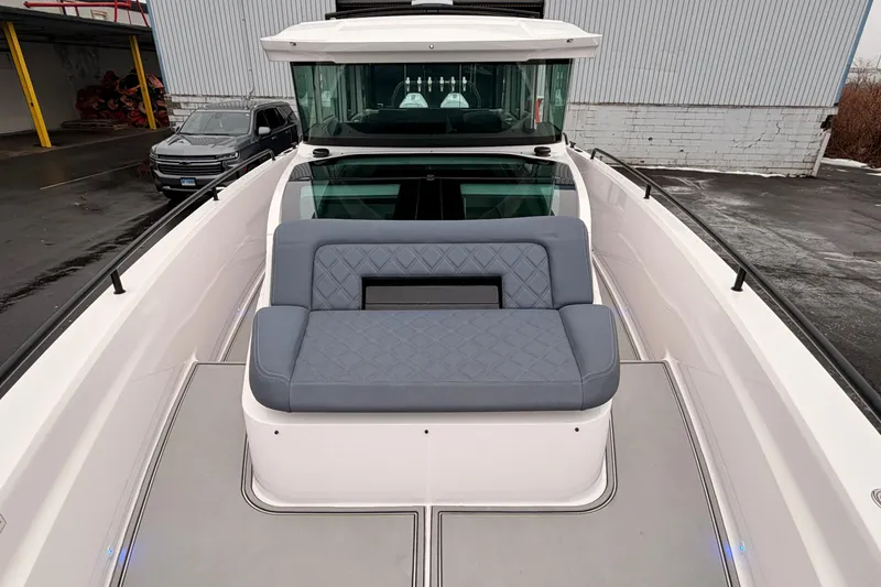 Slide: The Image of 2021 Axopar 37 XC Cross Cabin with gray seating on deck, docked near a building. - 12