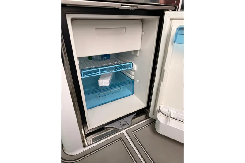 Slide: The Image of Open refrigerator inside 2021 Axopar 37 XC Cross Cabin boat, showing shelves and storage. - 22