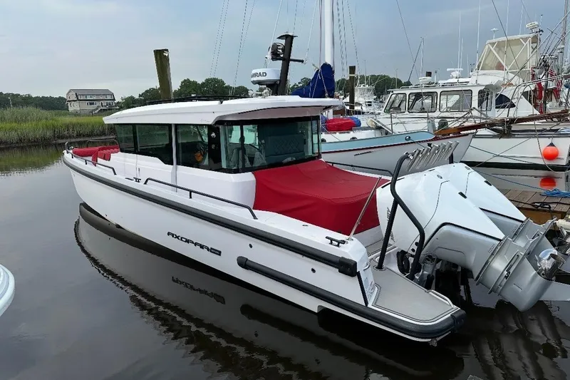 Slide: The Image of 2021 Axopar 37 XC Cross Cabin boat docked in a marina, featuring a red cover. - 5