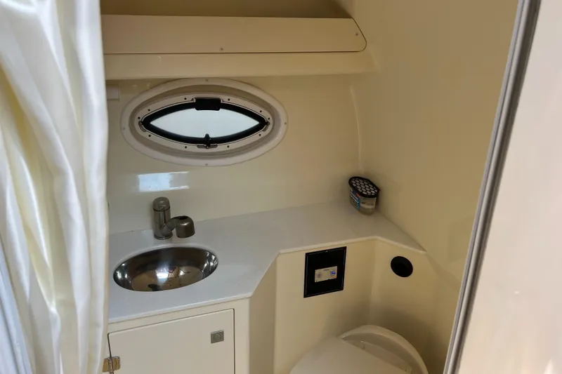 Slide: The Image of 2016 Monterey 295 Sport Yacht bathroom with sink, porthole, and toilet. - 15
