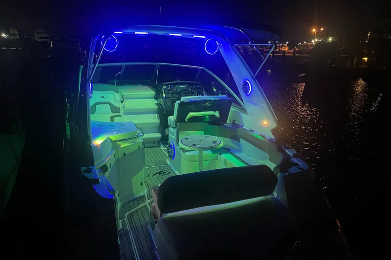 Slide: The Image of 2016 Monterey 295 Sport Yacht illuminated at night with vibrant blue and green lights. - 8