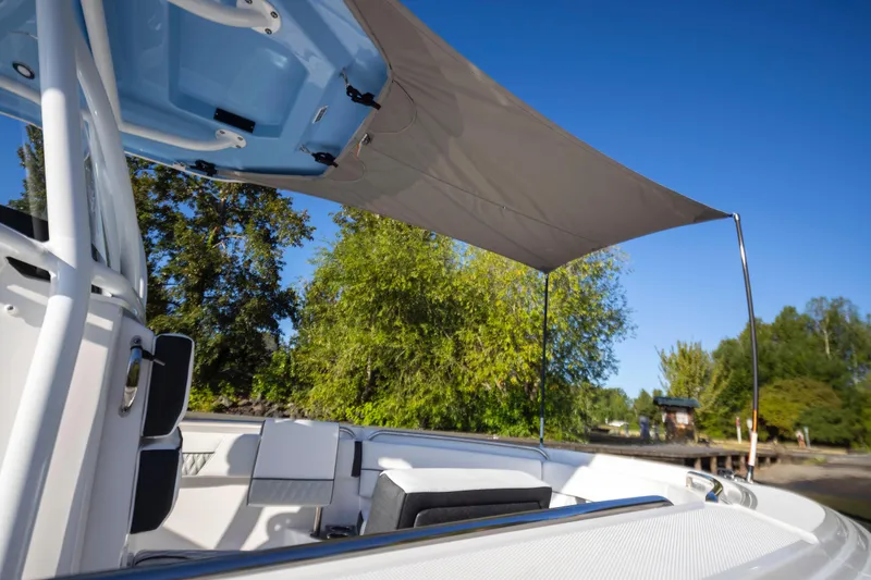 Slide: The Image of 2024 Blackfin 222 CC boat with sunshade, surrounded by lush greenery and clear blue sky. - 13