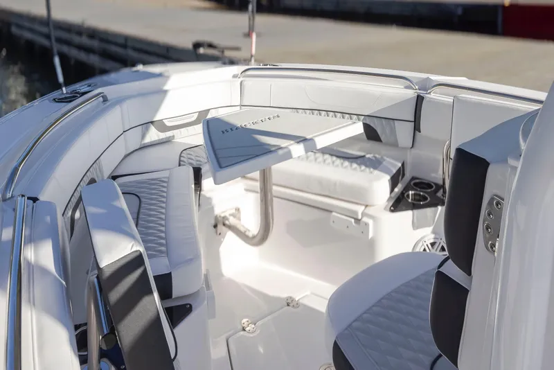 Slide: The Image of 2024 Blackfin 222 CC boat interior with white seating and table, dockside view. - 15
