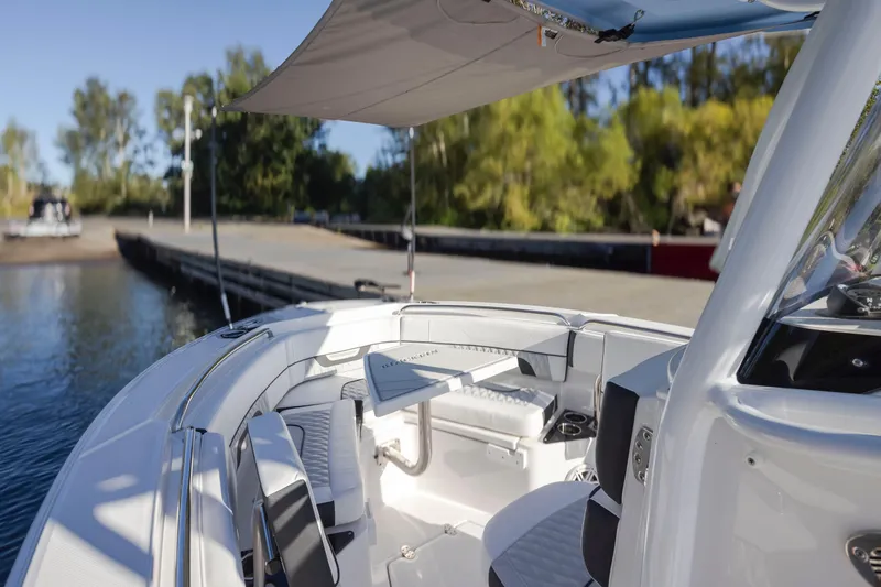 Slide: The Image of 2024 Blackfin 222 CC boat interior with seating and canopy, docked by a serene waterfront. - 16