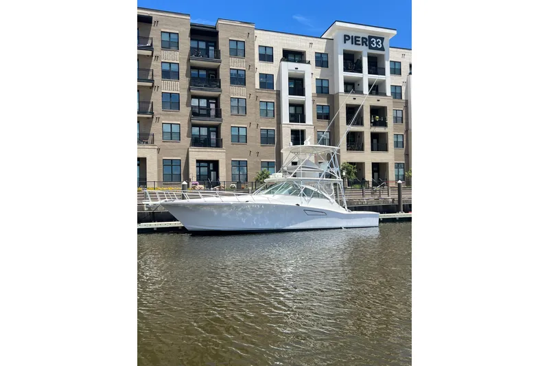 The Image of 2005 Cabo 45 Express yacht docked near Pier 33, modern building backdrop. - 1