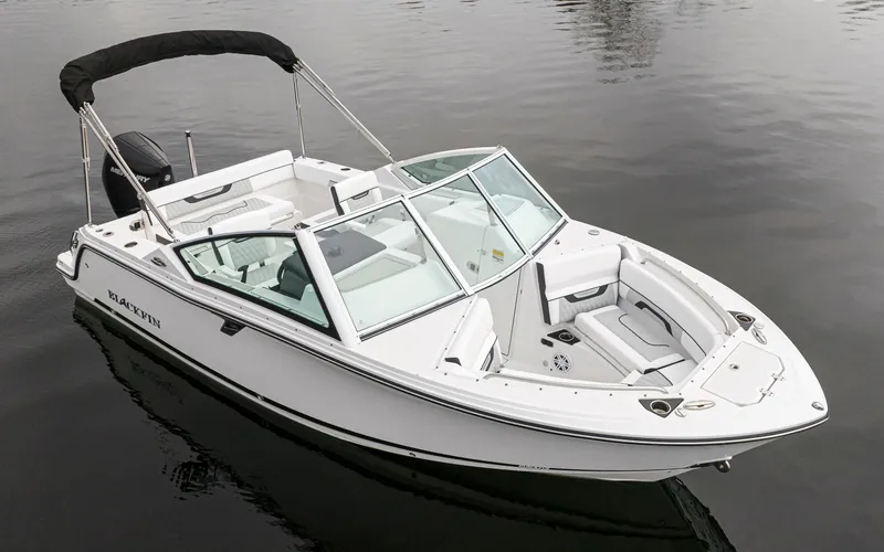 Slide: The Image of 2024 Blackfin 232DC Dual Console boat on calm water, featuring sleek design and spacious seating. - 2
