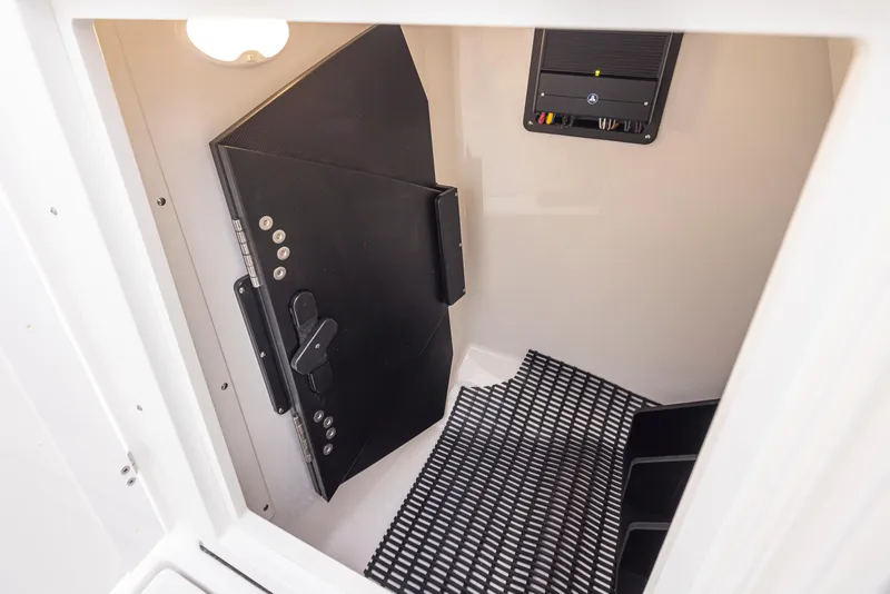 Slide: The Image of 2024 Blackfin 232DC interior storage compartment with black mat and secure door. - 29