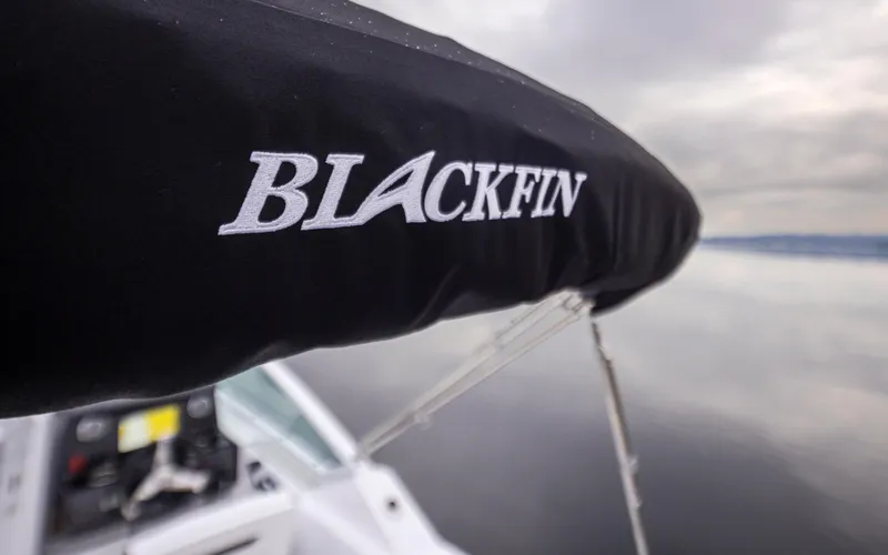 Slide: The Image of 2024 Blackfin 232DC Dual Console boat with logo on cover, calm water background. - 31