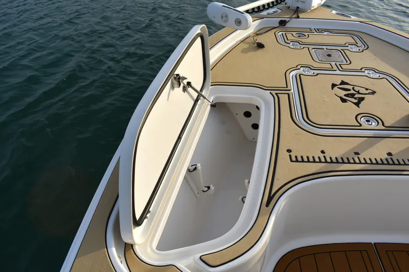 Slide: The Image of 2018 Sea Hunt BX 22 BR boat deck with open storage compartment, on calm water. - 6