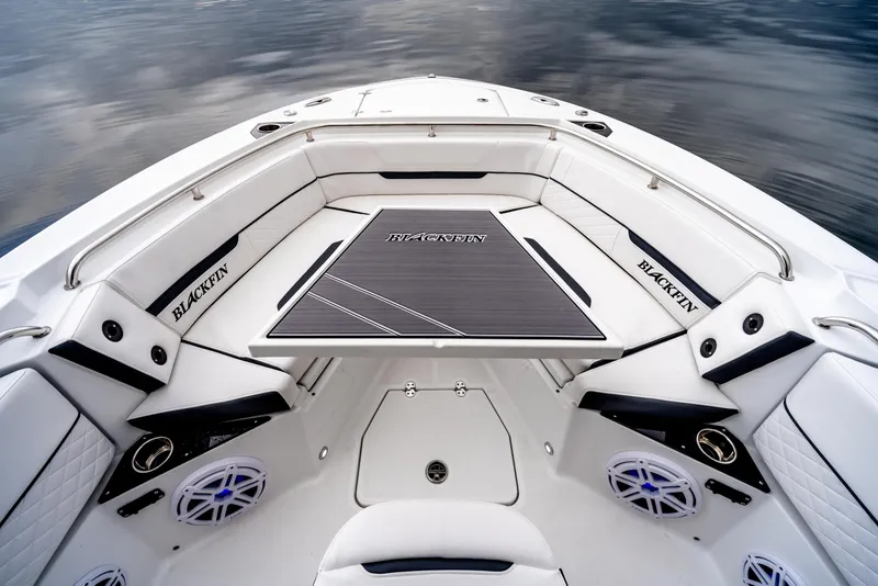 Slide: The Image of 2023 Blackfin 252 CC boat interior with sleek seating and table on calm water. - 11