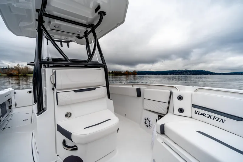 Slide: The Image of 2023 Blackfin 252 CC boat interior with seating, on a calm lake under cloudy skies. - 14