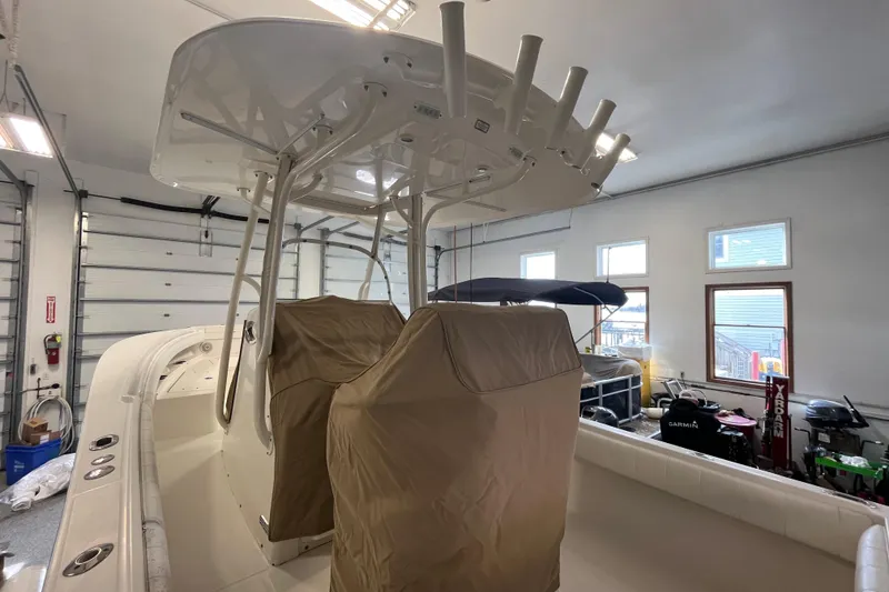 Slide: The Image of 2015 Regulator 25 boat interior in garage, featuring covered seats and rod holders. - 11