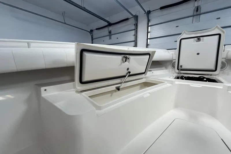 Slide: The Image of 2015 Regulator 25 boat storage compartments open in a garage setting. - 18