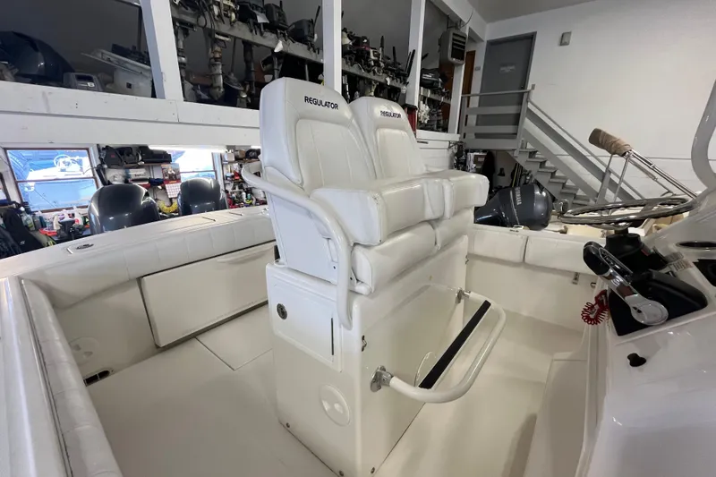 Slide: The Image of 2015 Regulator 25 boat interior with white seating and steering wheel in a garage. - 30