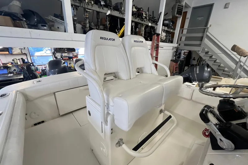 Slide: The Image of 2015 Regulator 25 boat interior with white seating and steering wheel in a workshop. - 31