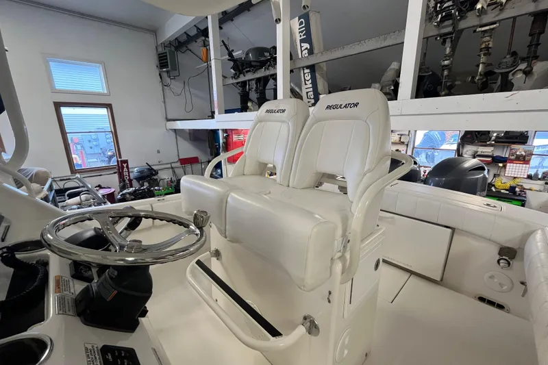 Slide: The Image of 2015 Regulator 25 boat interior with dual white captain's chairs and steering wheel. - 32