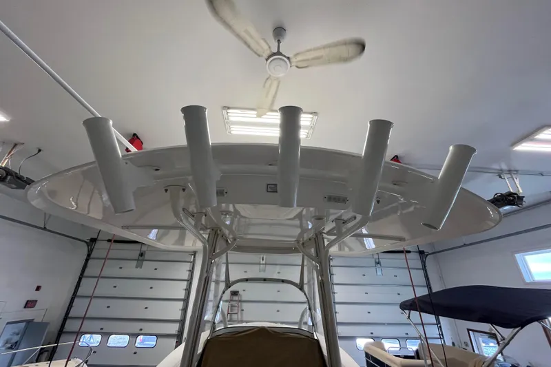 Slide: The Image of 2015 Regulator 25 boat in garage, featuring rod holders and overhead fan. - 56