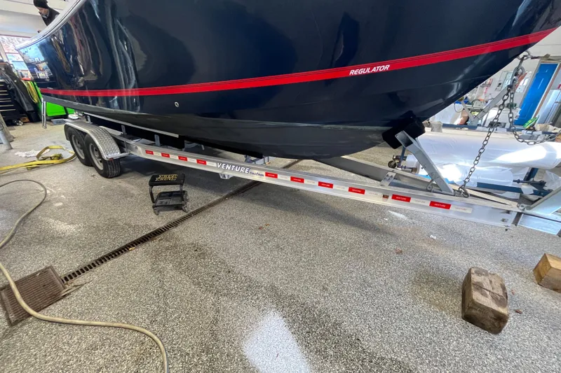 Slide: The Image of 2015 Regulator 25 boat on Venture trailer in a garage setting. - 58