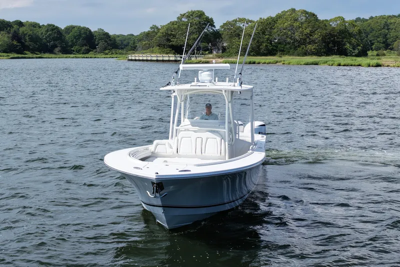 Slide: The Image of 2019 Regulator 34SS boat cruising on a scenic lake with lush greenery. - 11