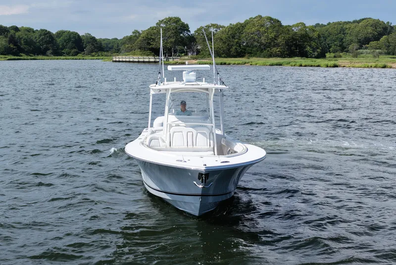 Slide: The Image of 2019 Regulator 34SS boat cruising on a scenic lake with lush green shoreline. - 12