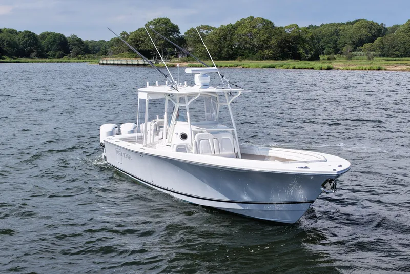 Slide: The Image of 2019 Regulator 34SS boat cruising on a scenic lake with lush green shoreline. - 13