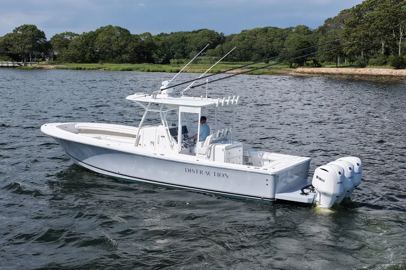 Slide: The Image of 2019 Regulator 34SS boat on water with triple Yamaha engines, near a wooded shoreline. - 8