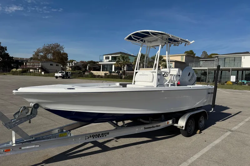 Slide: The Image of 2025 Savannah 210X boat on trailer, parked outdoors under clear blue sky. - 1
