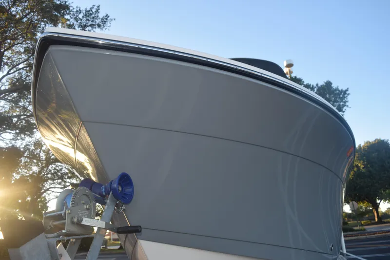 Slide: The Image of 2022 Cobia 220 Center Console boat on trailer, sunlit, with trees in background. - 13