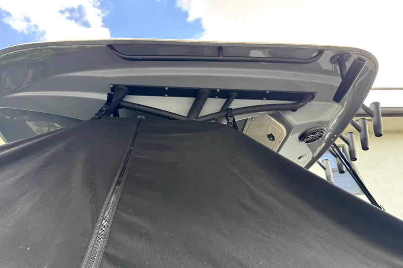 Slide: The Image of 2022 Cobia 220 Center Console boat with black cover, viewed from below against blue sky. - 18