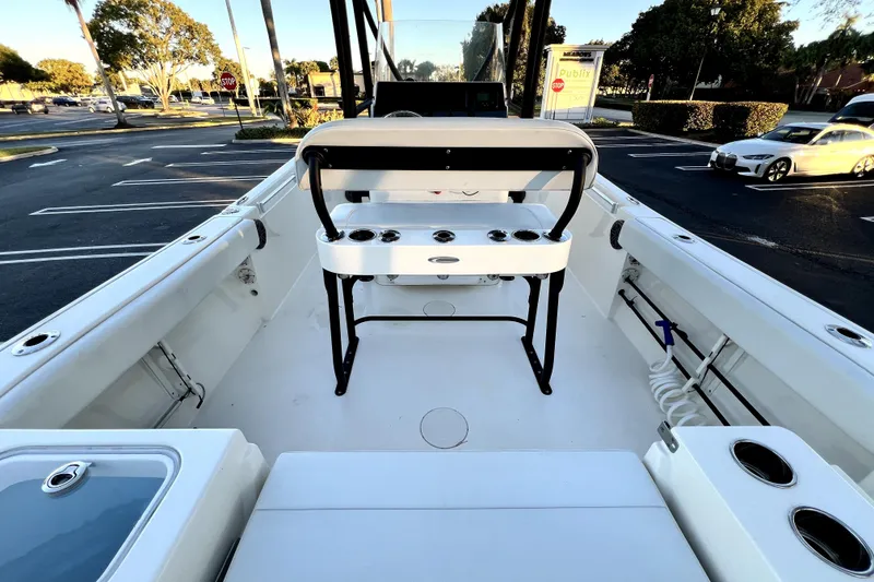 Slide: The Image of 2022 Cobia 220 Center Console boat interior with seating and rod holders in a parking lot. - 34