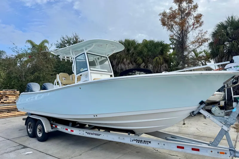 Slide: The Image of 2021 Sportsman Open 282 Center Console boat on trailer, surrounded by trees. - 5