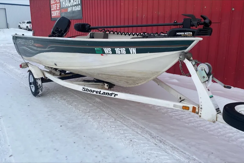 Slide: The Image of 2004 Crestliner Angler 1400 Tiller boat on ShoreLand'r trailer, parked on snowy ground. - 2