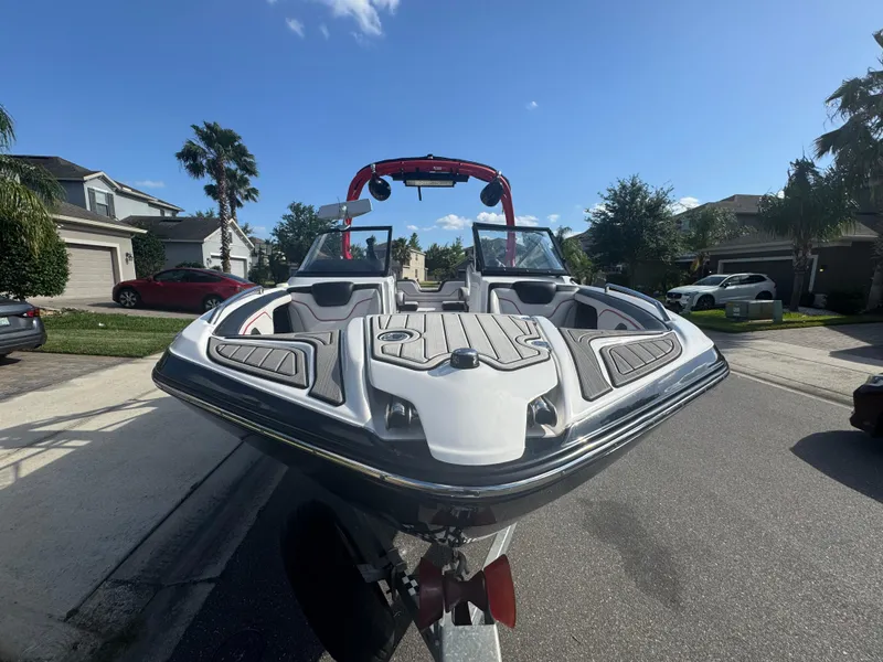 Slide: The Image of 2018 Yamaha Boats 212X on trailer, parked in suburban neighborhood under clear blue sky. - 17