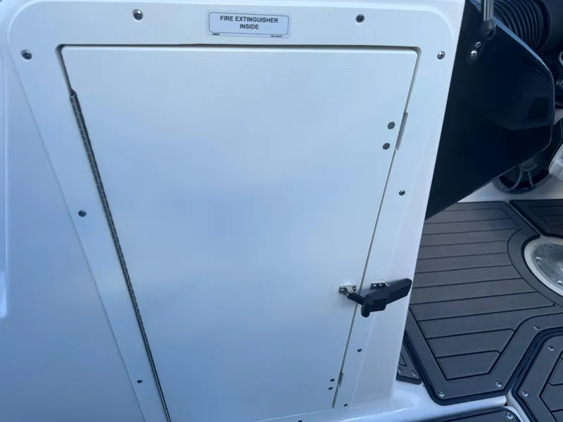 Slide: The Image of Fire extinguisher compartment on 2018 Yamaha Boats 212X, featuring secure latch and safety label. - 36