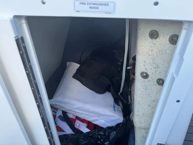 Slide: The Image of Storage compartment on a 2018 Yamaha Boats 212X, containing gear and a fire extinguisher. - 37