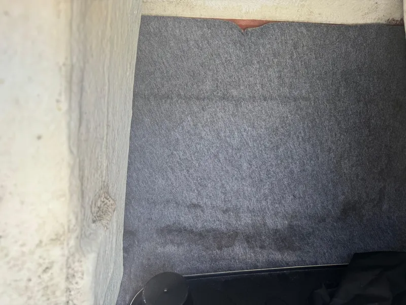 Slide: The Image of Interior storage compartment of a 2018 Yamaha Boats 212X, featuring gray carpeting. - 40