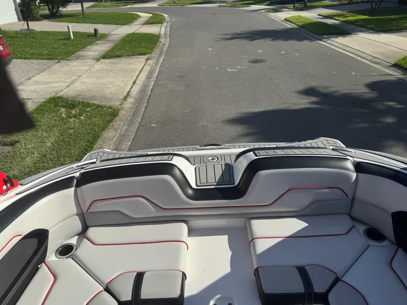 Slide: The Image of 2018 Yamaha Boats 212X interior, featuring sleek seating and modern design on a sunny street. - 46
