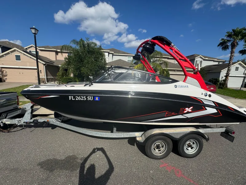 Slide: The Image of 2018 Yamaha Boats 212X on trailer, black and red design, parked in residential area. - 7