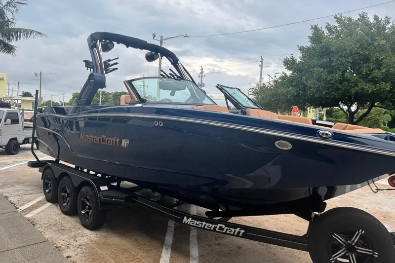 Slide: The Image of 2026 MasterCraft XT24 boat on trailer, parked outdoors, showcasing sleek design. - 12