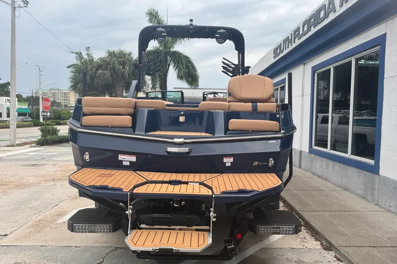 Slide: The Image of 2026 MasterCraft XT24 boat with teak deck, parked outside South Florida dealership. - 2