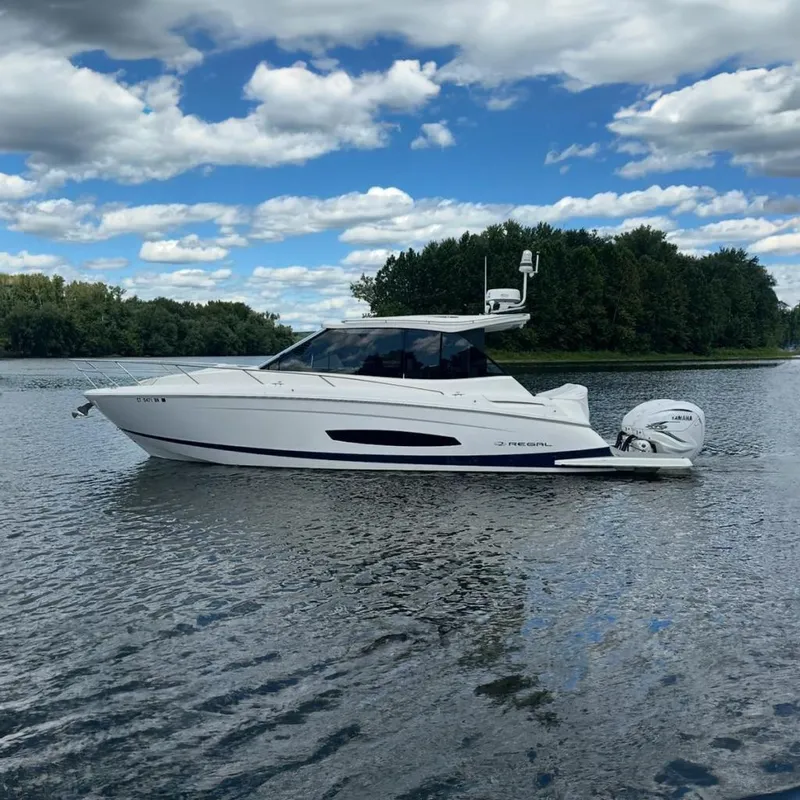The Image of 2022 Regal 36 XO boat on calm water under blue sky. - 0