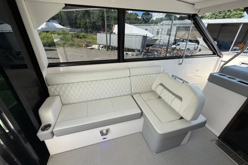 Slide: The Image of Interior seating of 2022 Regal 36 XO boat with white upholstery and large windows. - 26