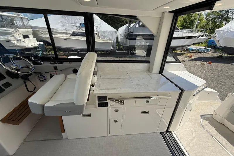 Slide: The Image of 2022 Regal 36 XO yacht interior with helm, seating, and cabinetry in a marina setting. - 27