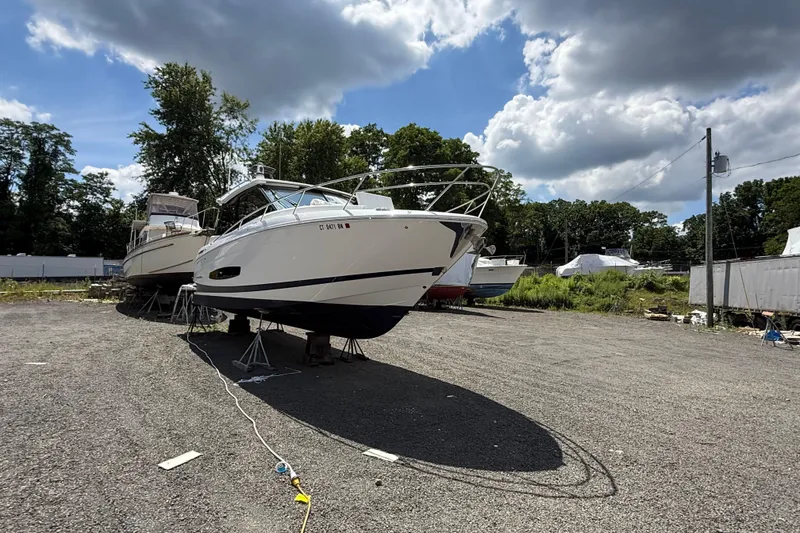 Slide: The Image of 2022 Regal 36 XO boat on stands in a gravel lot under a cloudy sky. - 4