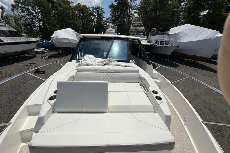 Slide: The Image of 2022 Regal 36 XO boat with white seating, docked outdoors among other vessels. - 47