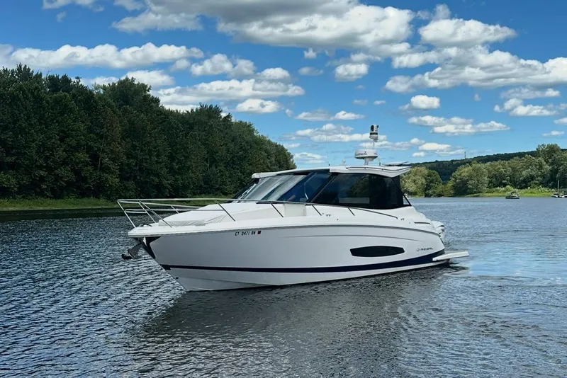 Slide: The Image of 2022 Regal 36 XO boat cruising on a scenic river under a blue sky. - 59